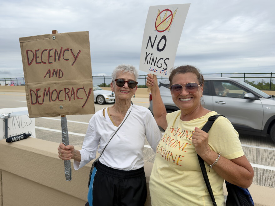 Linda Wruck, left, and Cindy Smith, right, hold signs at a No Kings rally along the Estero Parkway Bridge while some passing below on Interstate 75 and on the bridge honked their horns and waved in solidarity.