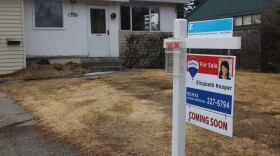 A for sale real estate sign in front of a dry grassy house