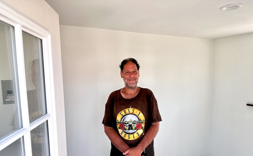  Man standing inside one-room shelter.