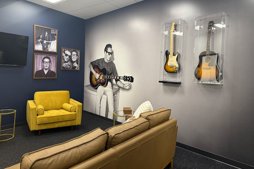 A green room has framed photos of Buddy Holly up alongside framed guitars.
