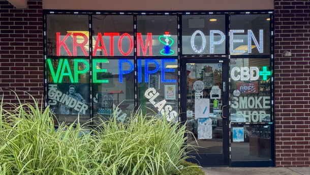 Storefront windows of a smoke shop advertising kratom in Oklahoma City.