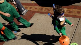 A boy walks past social distancing markers meant to help prevent the spread of the new coronavirus as he trick-or-treats for Halloween Saturday, Oct. 31, 2020, in downtown Overland Park, Kan. (AP Photo/Charlie Riedel)