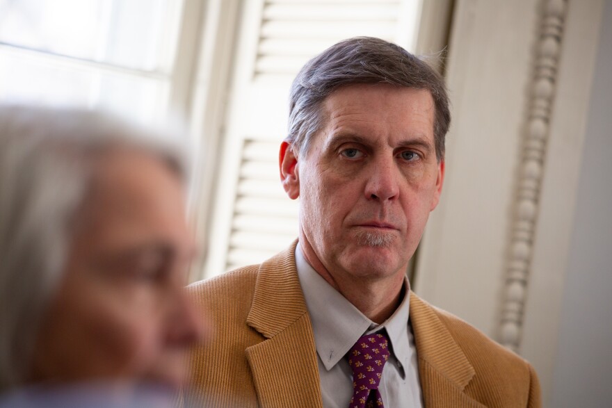 A man in a tan suit looks to the side