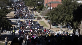Hundreds of people are packed into a street marching.