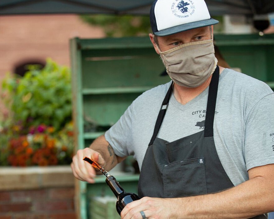 A staff member at The Regional restaurant in Fort Collins uncorks a bottle of wine.