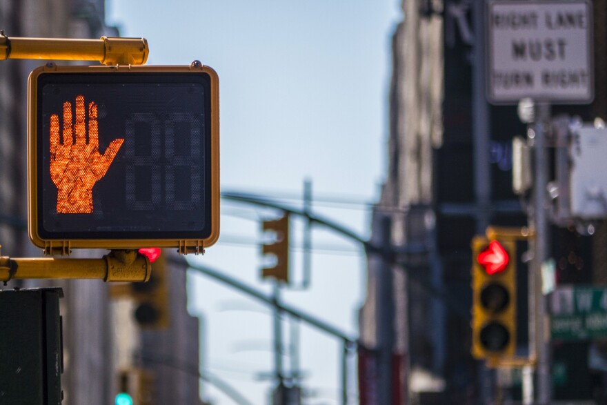 Photo of a street scene with a crosswalk sign in the foreground and a traffic light in the background with a sign that says "Right Lane Must Turn Right."