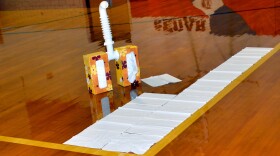Model of a human lung made from two tissue boxes and a white sewer pipe beside many tissues spread out on a gym floor. 