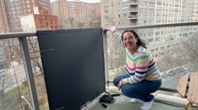 Lauren Phillips of the Bronx poses with her balcony solar panel. Rosemary Misdary/Gothamist