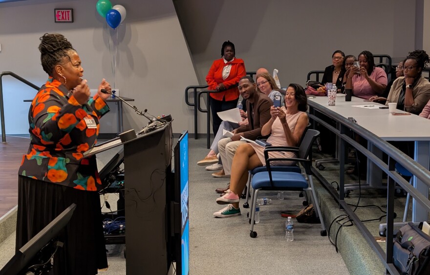 woman stands at podium in auditorium