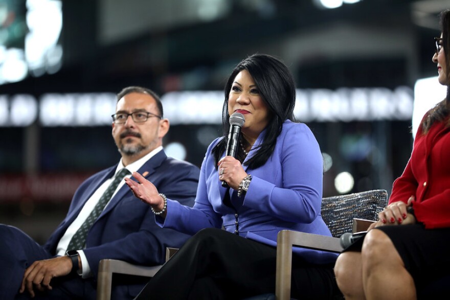 Woman in blue blazer speaks into microphone