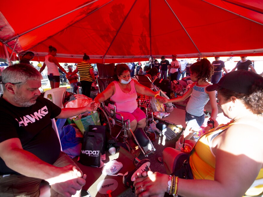 Wanda Santana, center, prays along members of her family at the makeshift camp located at the Mariano Rodríguez Coliseum in Guanica, Puerto Rico.