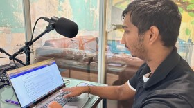 student sits in front of laptop and microphone