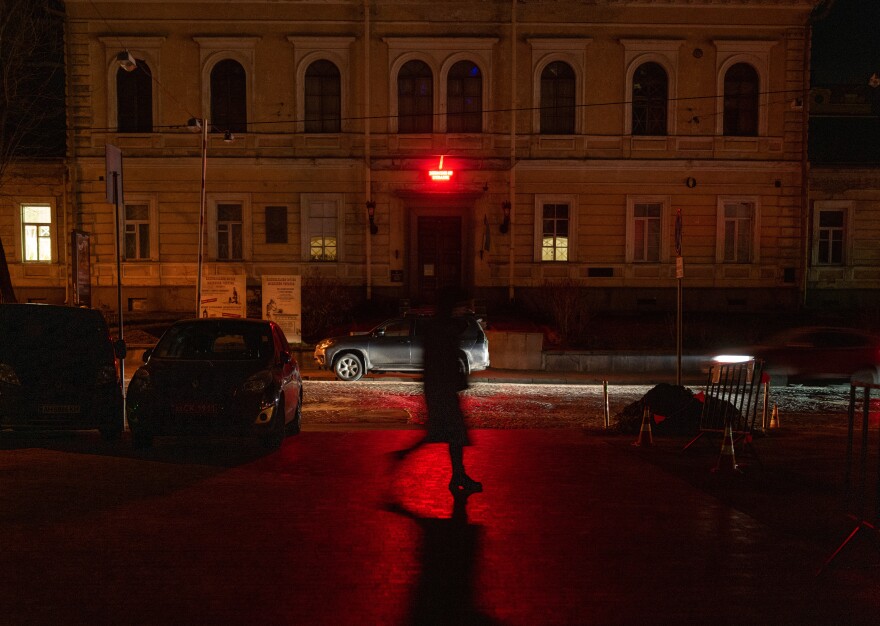 A woman walks through darkened Kyiv as many street lights remain off due to power shortages in the capital after numerous Russian air strikes on the country's energy infrastructure on Friday in Kyiv, Ukraine.