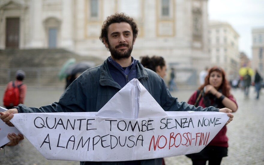 An Italian student holds a paper boat reading "How many tombs without names in Lampedusa, No to Bossi Fini" in reference to the recent tragedy near Lampedusa island where at least hundreds of immigrants drowned and the Bossi-Fini anti-immigration law.