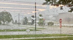 A blurry view through a car window as rain drops cover the glass