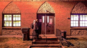 A man stands outside a shelter entrance at a church in Concord, NH.