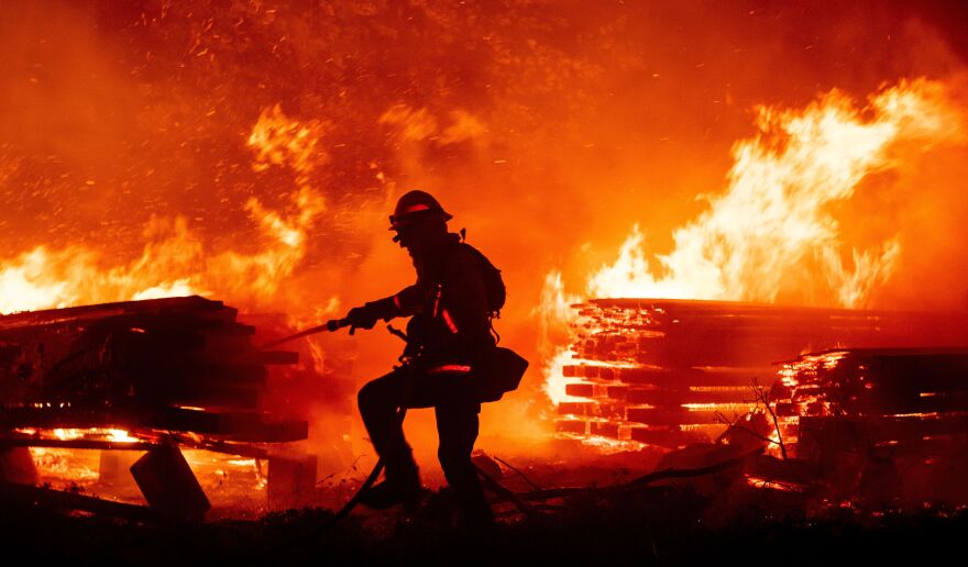 A firefighter douses flames as they push toward homes during the Creek Fire in the Cascadel Woods area of Madera County, Calif., on Sept. 7, 2020. FEMA denied 86% of claims during last year's fire season in California.