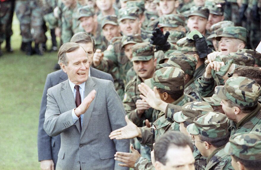 President George H. Bush is surrounded by soldiers as he walks by the stands at Ft. Stewart, Ga., after he addressed family members of the 24th Infantry Division stationed in Saudi Arabia and personnel at the facility on Friday, Feb. 1, 1991 outside of Hinesville, Ga.