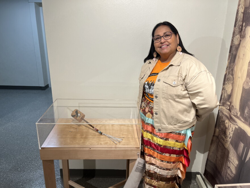 Photo of Monica Jo Raphael next to a rattle she made with porcupine quills