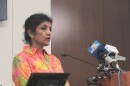 woman in floral-print dress stands at podium