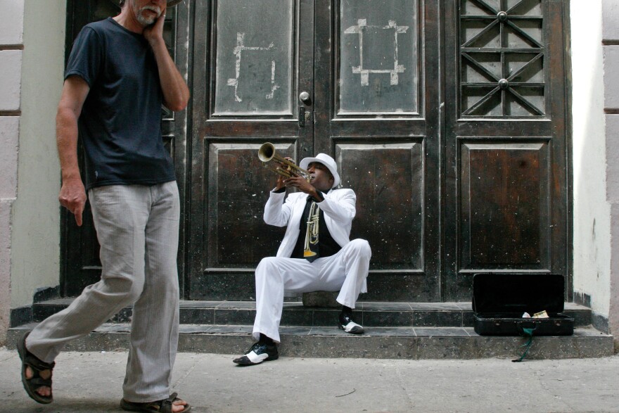 Tourists mill past a trumpet player in the restored part of Old Havana.