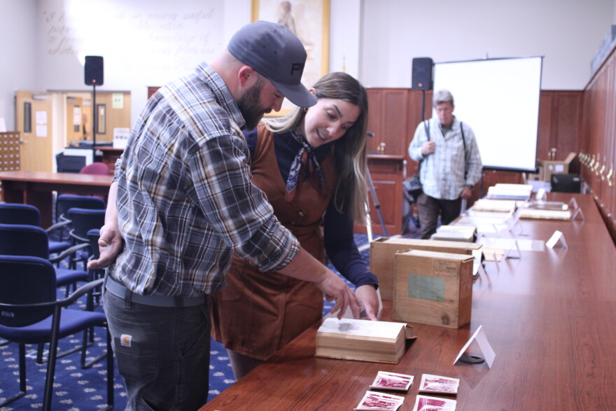 State Archivist Ashley Miller, back, shows off a 1911 record of the first election where a woman ran for governor as part of a showcase for American Archives month at the State Archives in Concord on Oct. 17, 2024.
