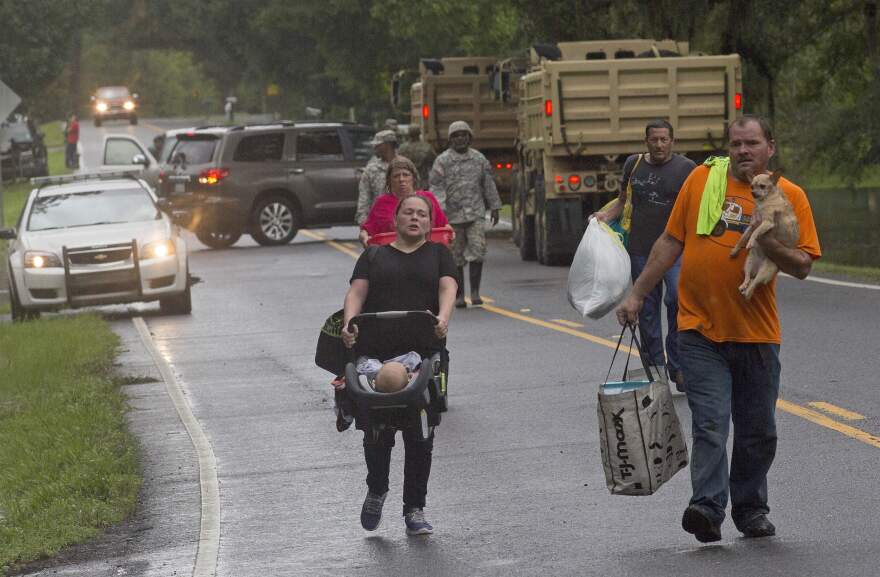 People are evacuated by members of the Louisiana Army National Guard near Walker, La., on Sunday.