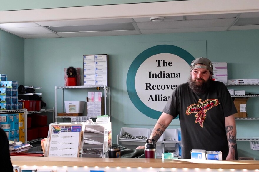 Scott Pietrovich stands behind the front desk of the Indiana Recovery Alliance. Supplies are stocked behind him.