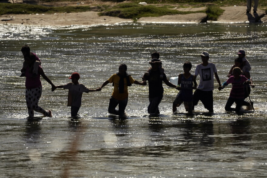 Migrants join hands as they cross the Rio Grande from Mexico into the U.S., Thursday, Sept. 21, 2023, in Eagle Pass, Texas. (AP Photo/Eric Gay)