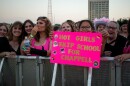 A young fan holds up a sign adorned with various LGBTQ+ pride stickers that reads, "Hot Girls Skip School For Chappell."