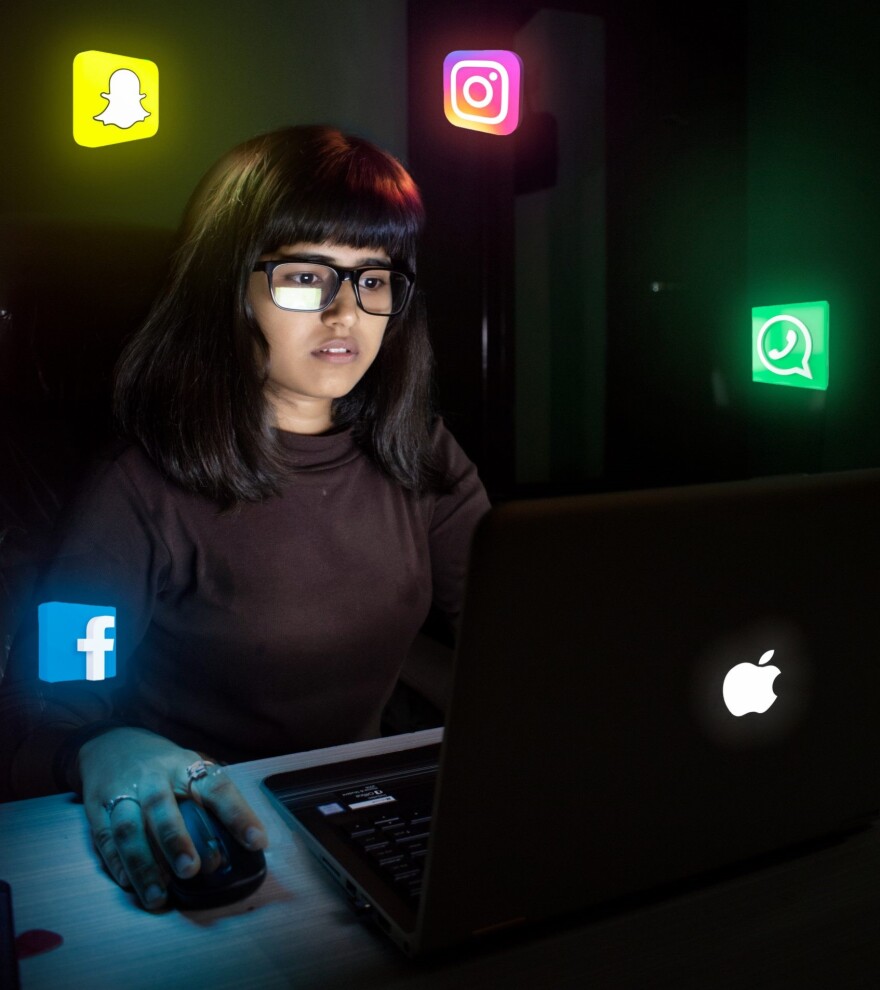 A girl looking into her laptop, with social media icons around her