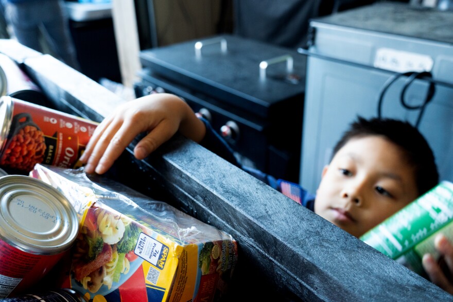 Cub Scout Elliot Ching, 6, of Pack 400 reaches over and tosses canned goods into a bin at the local fire station in Clayton, Mo. 