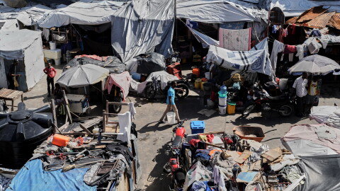 A man carries buckets of water where families displaced by gang violence are living in Port-au-Prince, Haiti, Wednesday, Aug. 12, 2026.