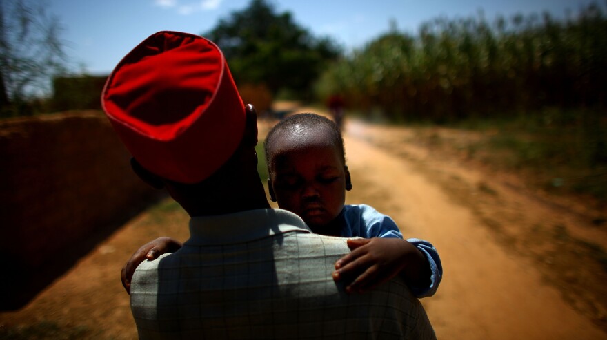 Ado Ibrahim carries his son Aminu through a village in northern Nigeria. Aminu was paralyzed by polio in August.