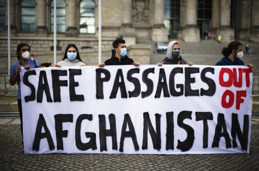 People hold a poster demanding a safe passage out of Afghanistan, during a demonstration in Berlin, Germany, Tuesday, Aug. 17, 2021.