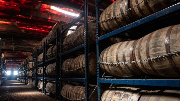 Many barrels filled with bourbon and whiskey line the interior of a barge.