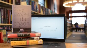 A laptop computer next to a stack of books