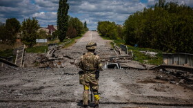 A soldier of the Kraken Ukrainian special forces unit observes the area at a destroyed bridge on the road near the village of Rus'ka Lozova, north of Kharkiv, on May 16, 2022. (Dimitar Dilkoff/AFP via Getty Images)