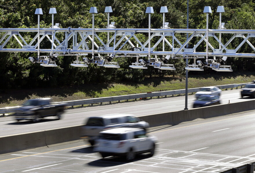 Cars pass under toll sensor gantries hanging over the Massachusetts Turnpike in Newton, Mass. 
