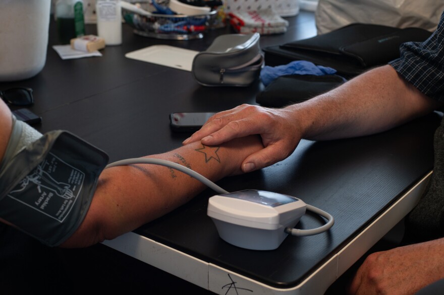 Robey holds the hand of a patient to calm them down while taking their blood pressure.