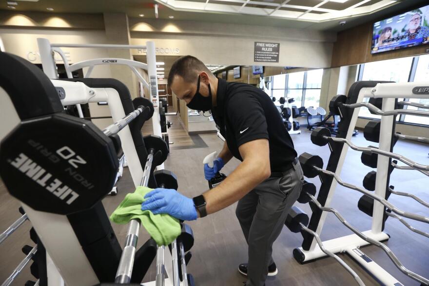 Jason Nichols, facilities operation manager, disinfects equipment at the Life Time Biltmore as it opens for business after being closed due to the coronavirus Monday, May 18, 2020, in Phoenix.