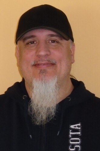 A man with a long grey beard and black baseball cap.