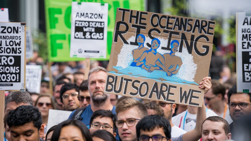 A protester holds a sign reading "The Oceans Are Rising But So Are We" at an Amazon employee walkout in Seattle, as part of the Global Climate Strike on Sept. 20, 2019. At some companies, employees are putting increasing pressure on their bosses to act on climate change.