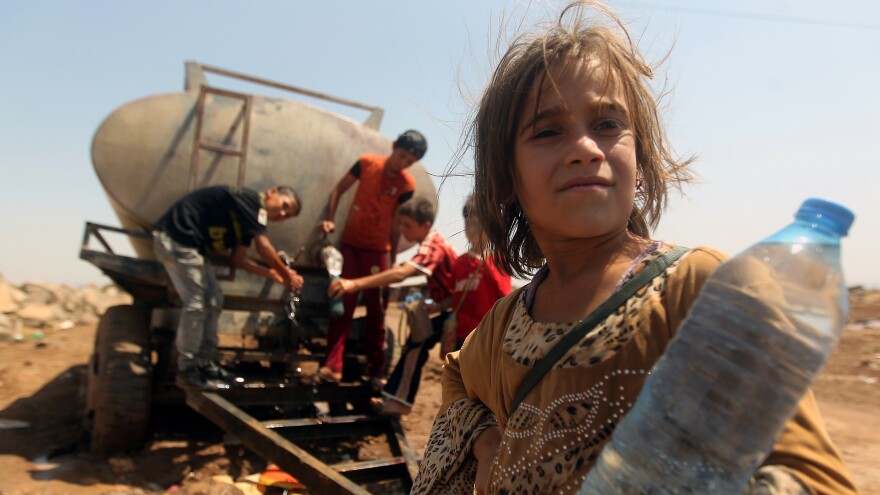 Young Iraqi Yazidi refugees fill bottles with water at the Newroz camp in northeastern Syria on Aug. 14, after fleeing advances by Islamic State jihadists in Iraq.