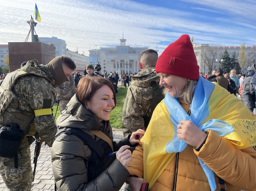 Hanna Malyar, Ukraine's deputy defense minister (center), signs a Ukrainian flag belonging to a local resident in Kherson on Monday. "Ukraine's success depends on two points," Malyar told NPR. "First our strength, our ability to fight. And second, the weapons that we receive from our partners," referring to the United States and other Western nations.