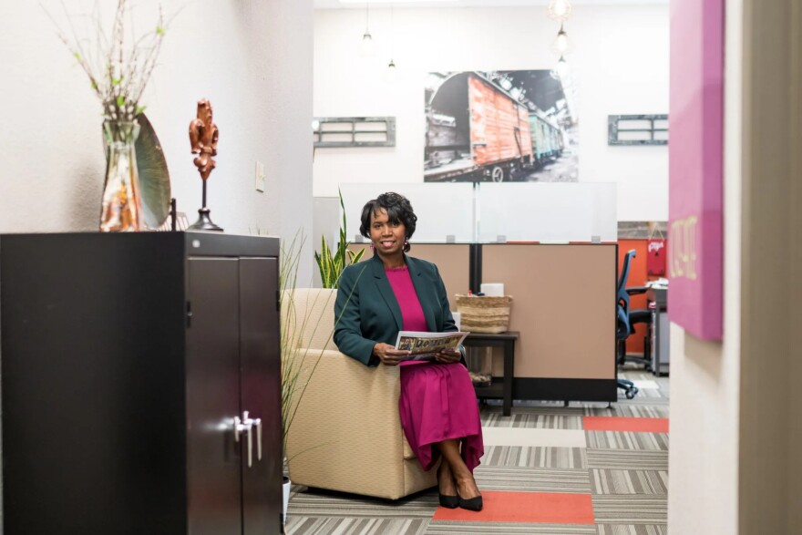 An image of a woman sitting on a chair holding a magazine in her lap.
