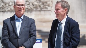From left: Indiana Gov. Mike Braun and Indianapolis Mayor Joe Hogsett share a laugh during the Indianapolis 500 Festival “kickoff to May” event at Monument Circle on Wednesday, April 29, 2026. Braun is a white man with gray hair and glasses. He's wearing a dark blue suit with a light blue and white striped shirt and a silver watch. Hogsett is a white man wearing a navy suit and a white shirt with a blue patterned tie. 