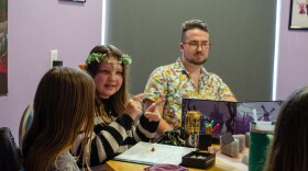 Mia Leonard, wearing elf ears and a floral crown, talks with other players during a recent Friday Dungeons & Dragons meetup. Gamemaster Brett Paul, on right, organizes the sessions as a means of helping the children develop. (Matthew Cupelli/WUFT News)