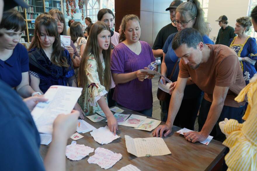 Audience members examine clues during an immersive theatrical murder mystery at the Soldotna Public Library in Soldotna, Alaska, on Wednesday, July 29, 2026.