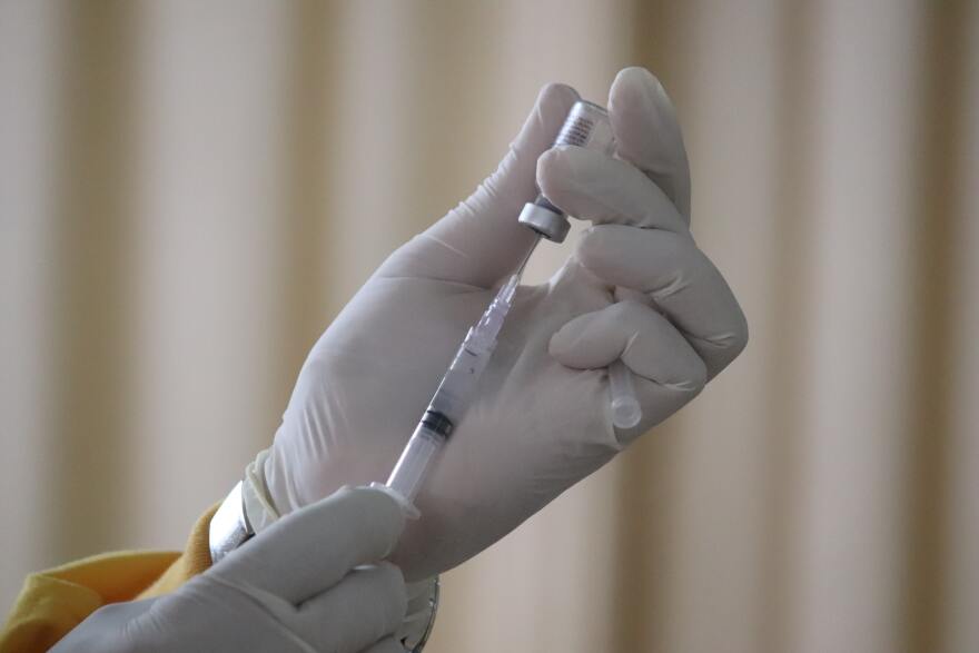 a person wearing medical gloves prepares a vaccine